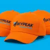 Три оранжевые бейсболки SkyPeak Logistics каскадом в ракурсе три четверти с вышивкой на передней панели