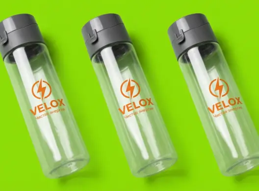 Три прозрачные бутылки для воды VELOX на ярко-салатовом фоне, расставленные под углом друг к другу