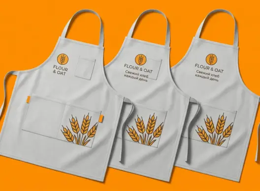 Три серых фартука с ДТФ-печатью FLOUR & OAT, расположены внахлёст под углом три четверти