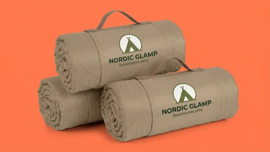 Три свернутых бежевых пледа Nordic Glamp сложены стопкой, логотип на переднем клапане