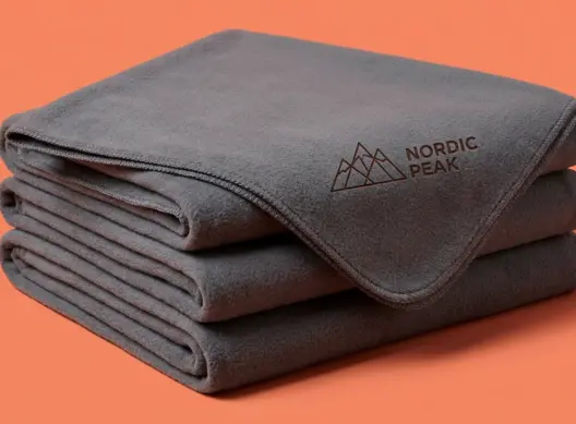 Три флисовых пледа Nordic Peak сложены стопкой, на верхнем — лазерная гравировка в углу