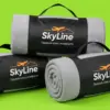 Три пледа SkyLine в чёрных чехлах-переносках, сложенные пирамидой на салатовом фоне