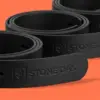 Три кожаных ремня Stone Oak свёрнуты спиралью и выстроены под углом, тиснение логотипа на кончике переднего изделия