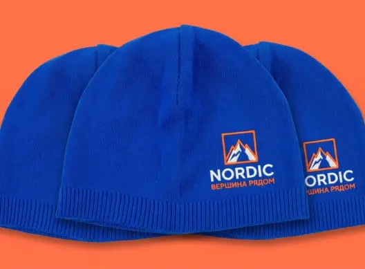 Три синие шапки бини Nordic Peak с вышивкой, уложены внахлёст, ракурс три четверти