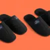 Две пары чёрных тапочек Hygge Way на коралловом фоне, вид под углом три четверти