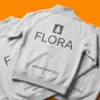 Три серые толстовки FLORA внахлест, крупный логотип на спинке, оранжевый фон