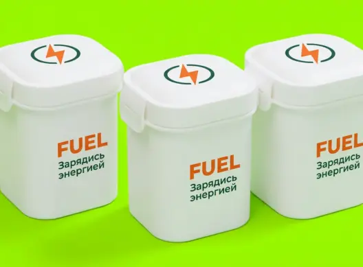 Три белых ланч-бокса FUEL в оранжево-зелёной графике на салатовом фоне, ракурс три четверти