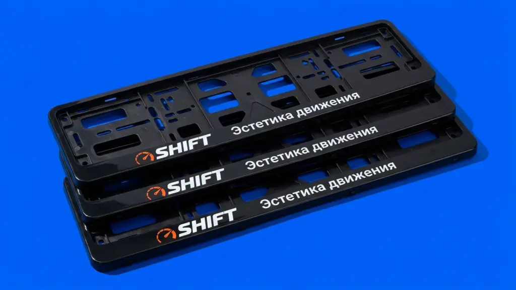 Три глянцевые рамки для номера SHIFT уложены каскадом под углом, оранжевый логотип контрастирует с чёрным пластиком