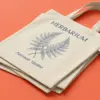 Три шопера Herbarium с ботаническим принтом, сложенные каскадом под углом на коралловом фоне