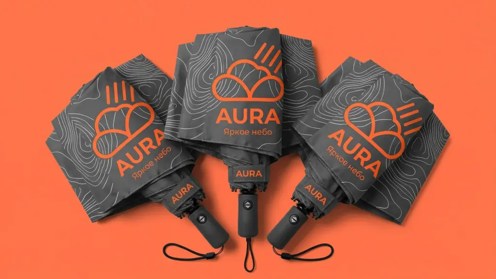 Три складных зонта Aura веером на коралловом фоне — крупные оранжевые логотипы на тёмно-серых куполах
