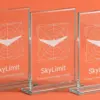 Три стеклянные стелы SkyLimit в ракурсе три четверти — свет преломляется сквозь прозрачные грани