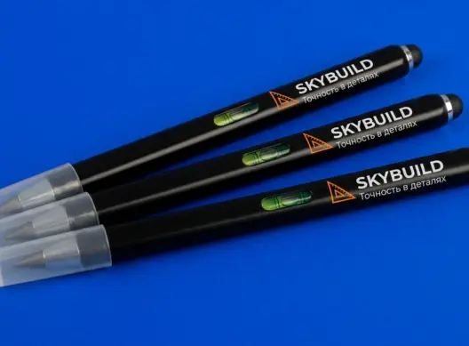 Три вечных карандаша SKYBUILD веером на синем фоне — видна брендированная зона и встроенный уровень