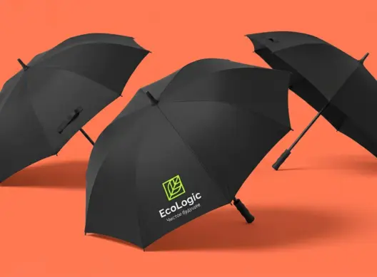 Три чёрных зонта-трости EcoLogic в динамичной композиции на коралловом фоне, логотип виден на переднем плане